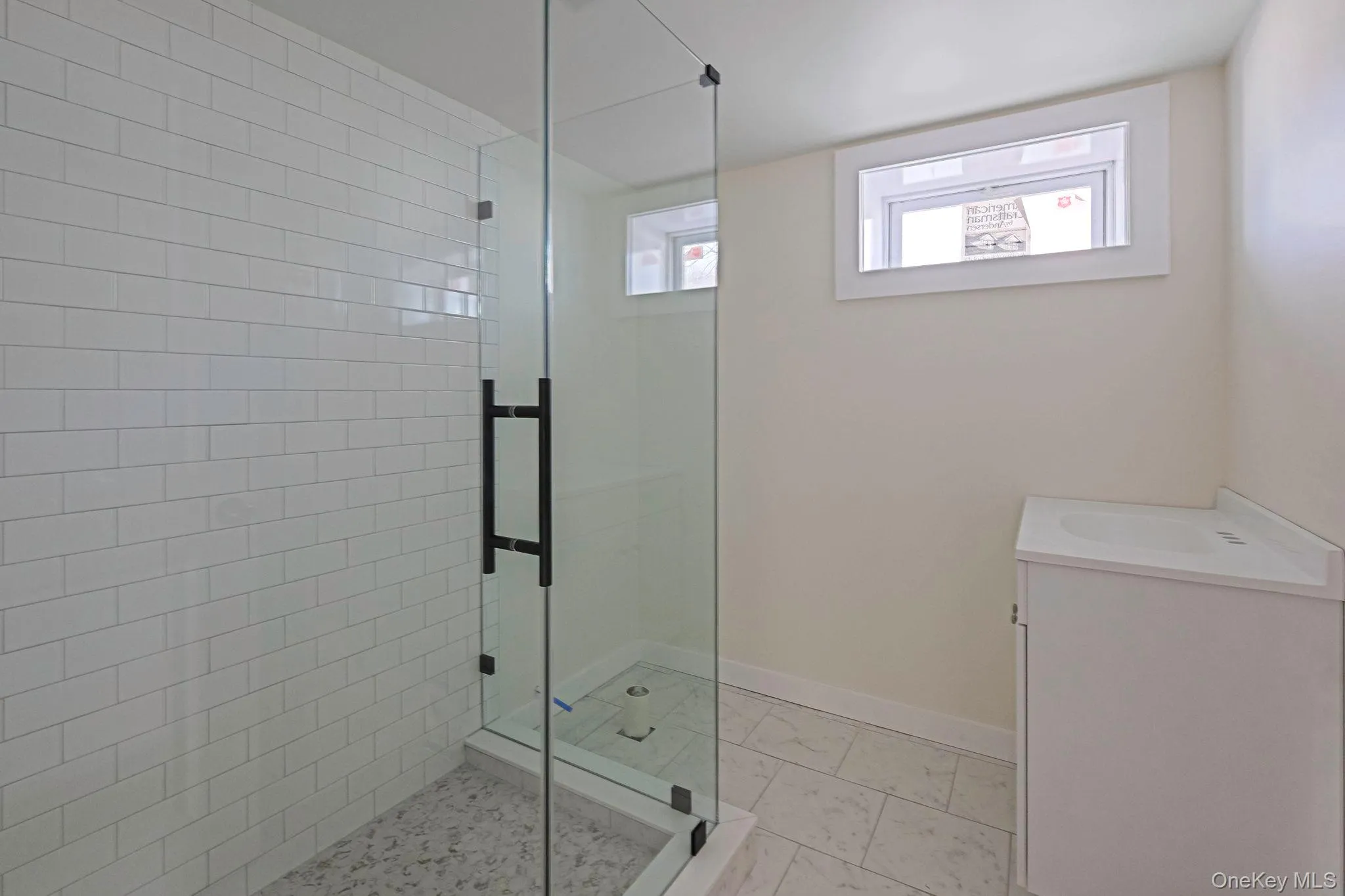 Bathroom with a stall shower, vanity, and marble finish floors Bathroom with a stall shower, vanity, and marble finish floors