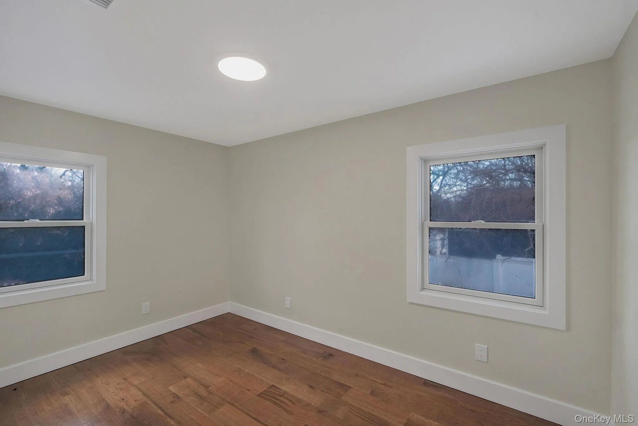 Empty room featuring dark wood-type flooring and baseboards Empty room featuring dark wood-type flooring and baseboards