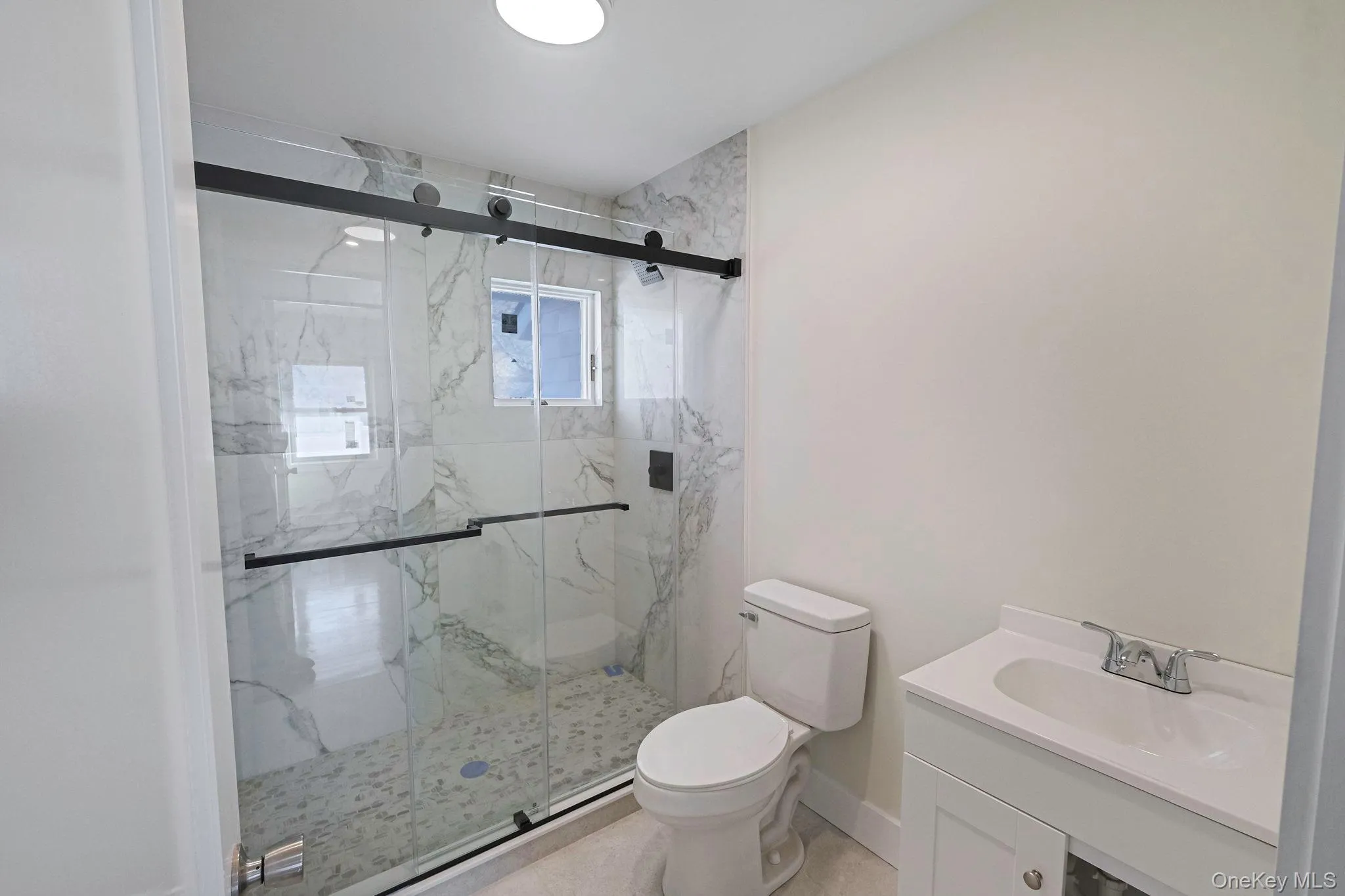 Full bath featuring vanity and a marble finish shower Full bath featuring vanity and a marble finish shower