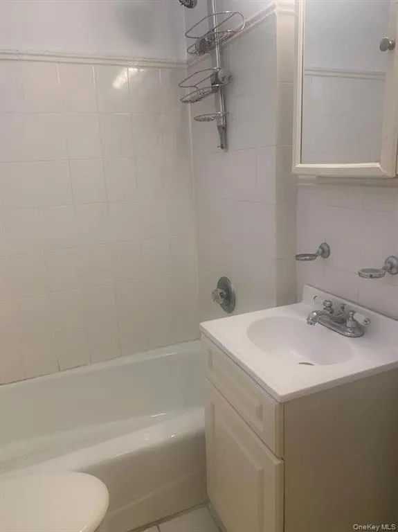 Bathroom featuring tile walls, vanity, shower combination, backsplash, and tile patterned flooring Bathroom featuring tile walls, vanity, shower combination, backsplash, and tile patterned flooring