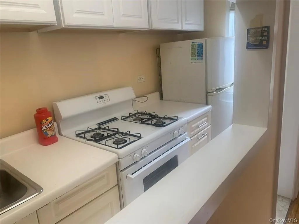 Kitchen featuring white appliances, white cabinetry, and light countertops Kitchen featuring white appliances, white cabinetry, and light countertops