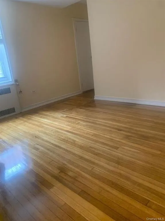 Unfurnished room with radiator and light wood finished floors Unfurnished room with radiator and light wood finished floors