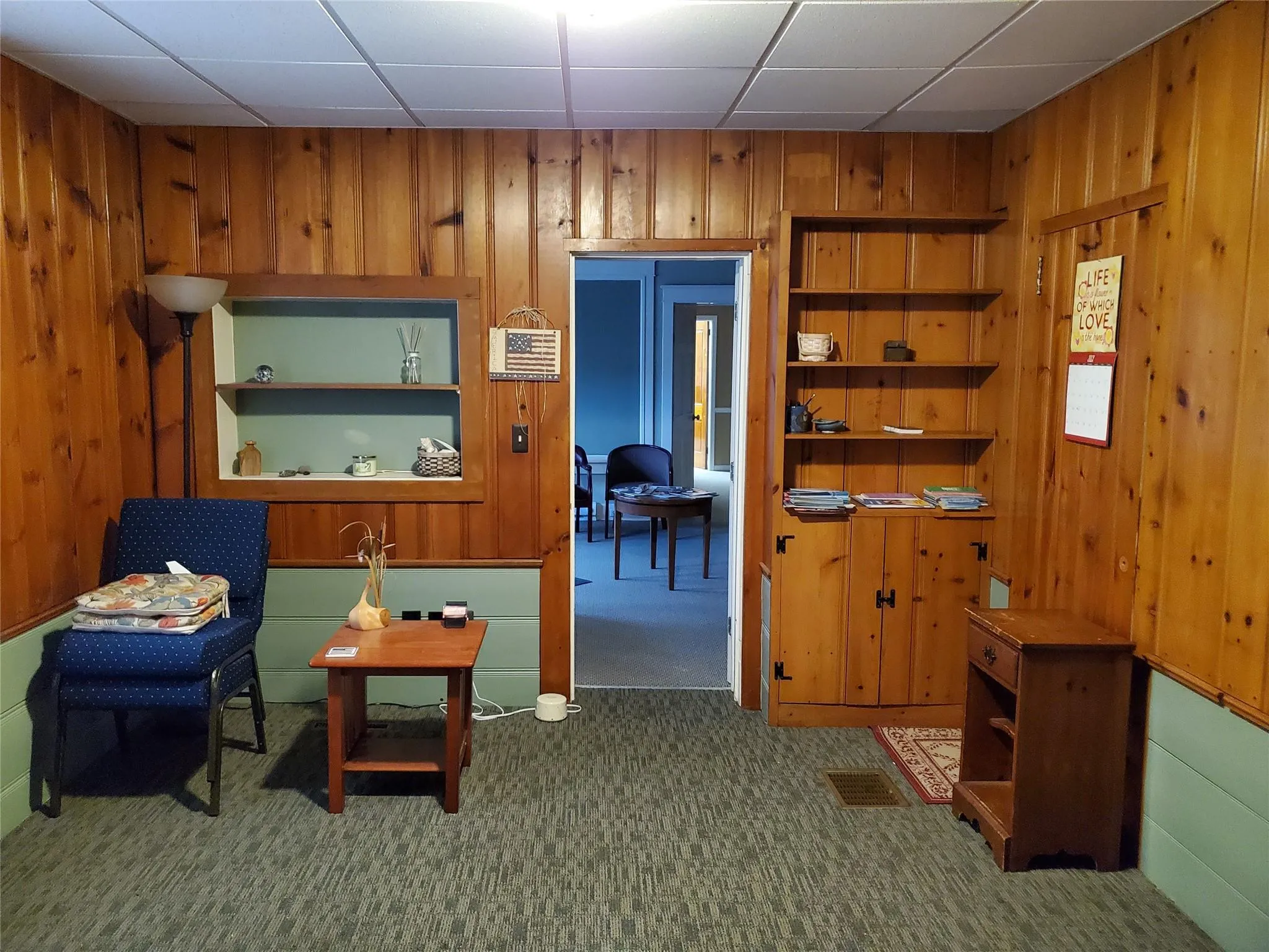 Living area featuring wood walls, carpet, and built in shelves Living area featuring wood walls, carpet, and built in shelves