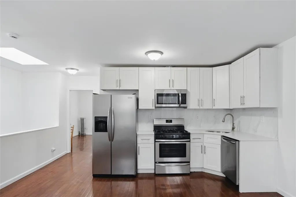 Kitchen with appliances with stainless steel finishes, light countertops, dark wood-type flooring, and white cabinets Kitchen with appliances with stainless steel finishes, light countertops, dark wood-type flooring, and white cabinets