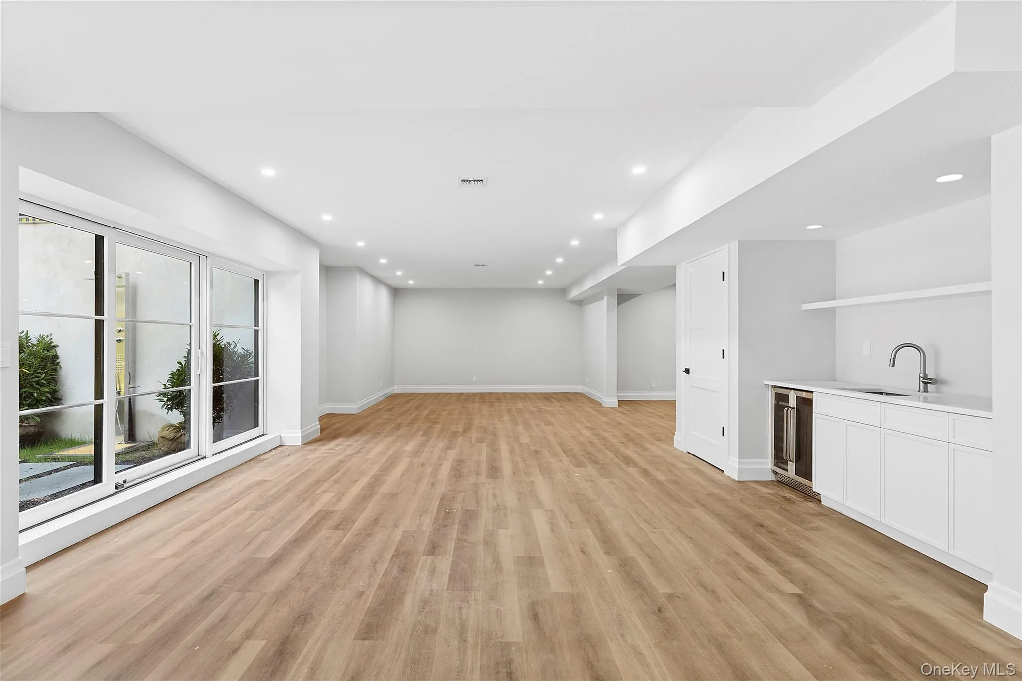 Unfurnished living room with light wood finished floors, recessed lighting, and beverage cooler Unfurnished living room with light wood finished floors, recessed lighting, and beverage cooler
