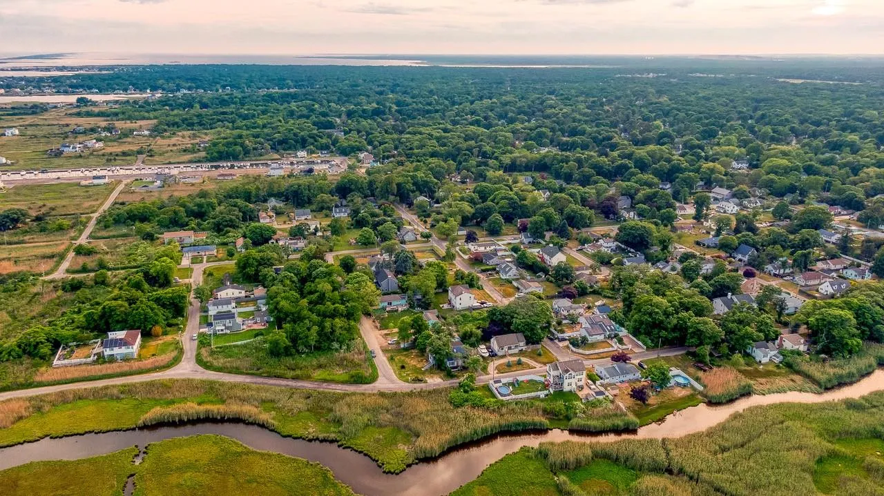 Aerial view of property and surrounding area featuring a nearby body of water and nearby suburban area Aerial view of property and surrounding area featuring a nearby body of water and nearby suburban area
