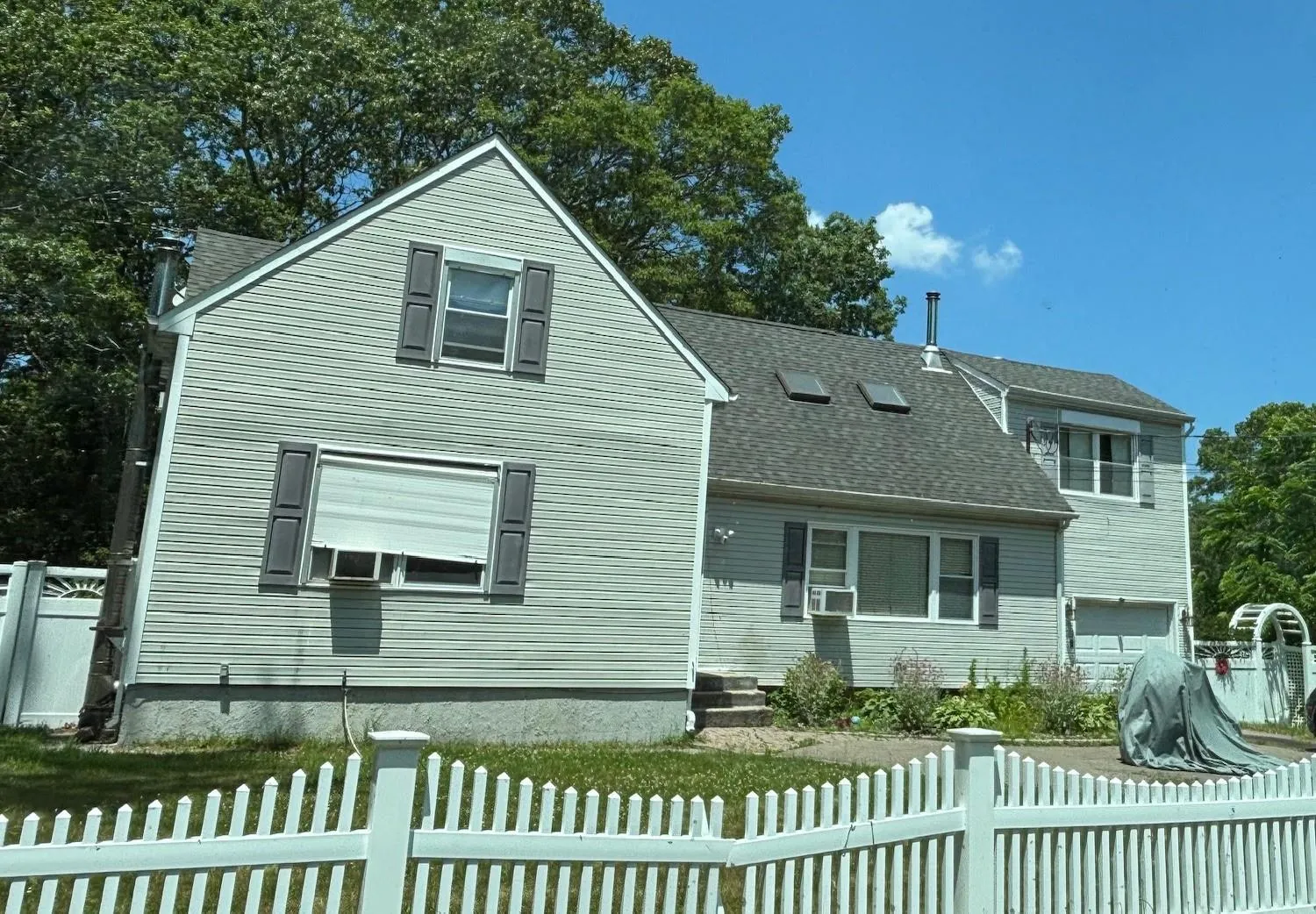 Traditional home featuring a shingled roof, a fenced front yard, and a garage Traditional home featuring a shingled roof, a fenced front yard, and a garage