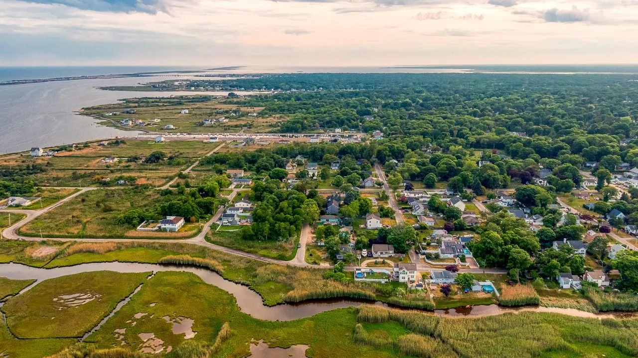 Aerial view of property's location featuring a large body of water and nearby suburban area Aerial view of property's location featuring a large body of water and nearby suburban area