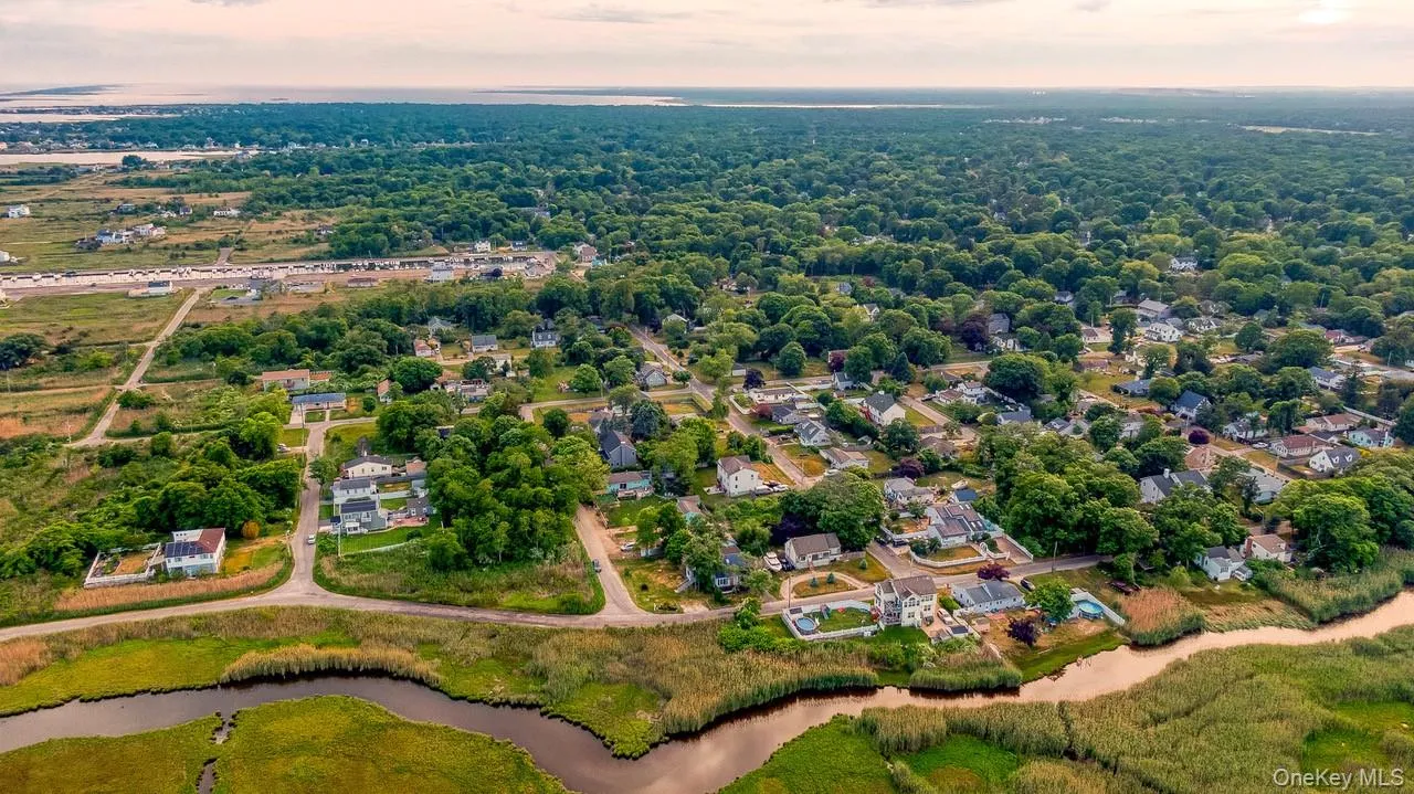 Aerial view of property and surrounding area featuring a nearby body of water and nearby suburban area Aerial view of property and surrounding area featuring a nearby body of water and nearby suburban area