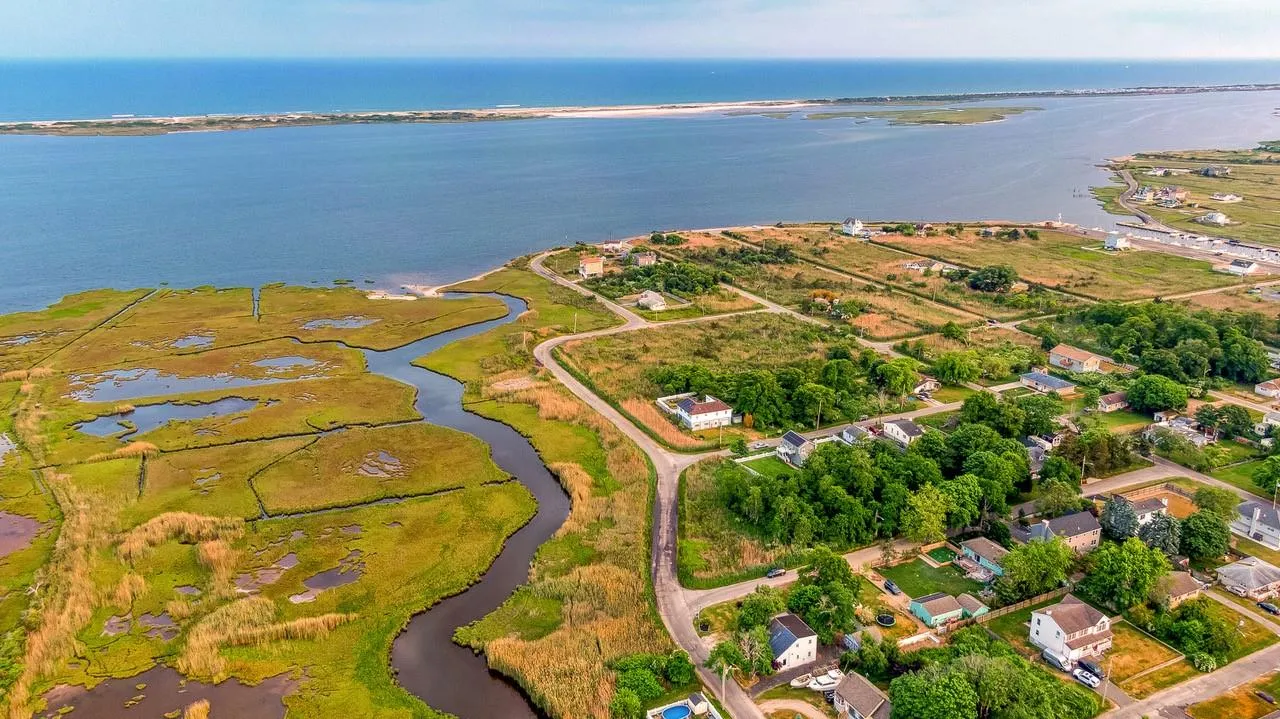 Aerial view of property and surrounding area featuring a large body of water and nearby suburban area Aerial view of property and surrounding area featuring a large body of water and nearby suburban area