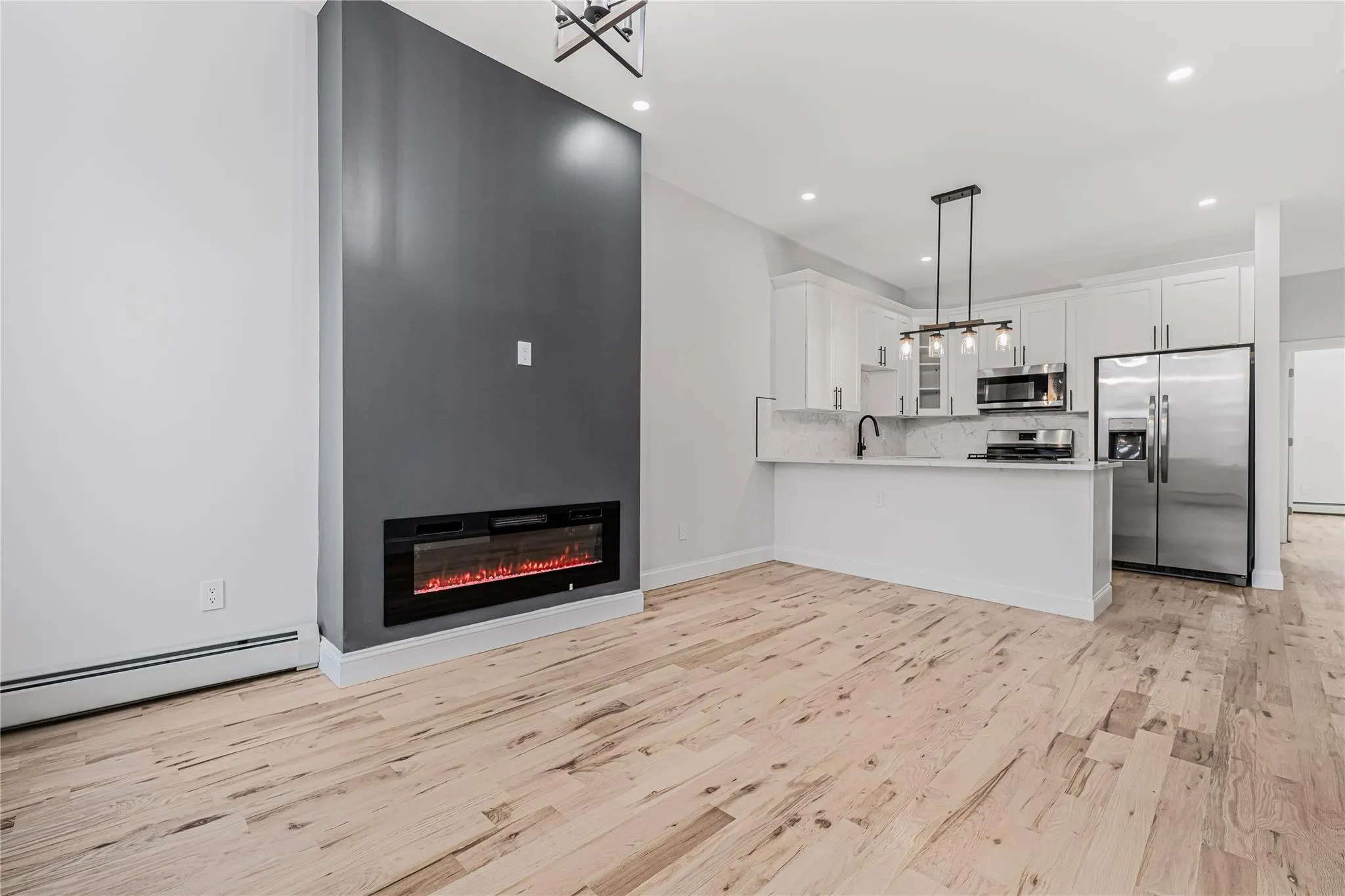 Kitchen with appliances with stainless steel finishes, light wood-type flooring, a peninsula, white cabinets, and recessed lighting Kitchen with appliances with stainless steel finishes, light wood-type flooring, a peninsula, white cabinets, and recessed lighting
