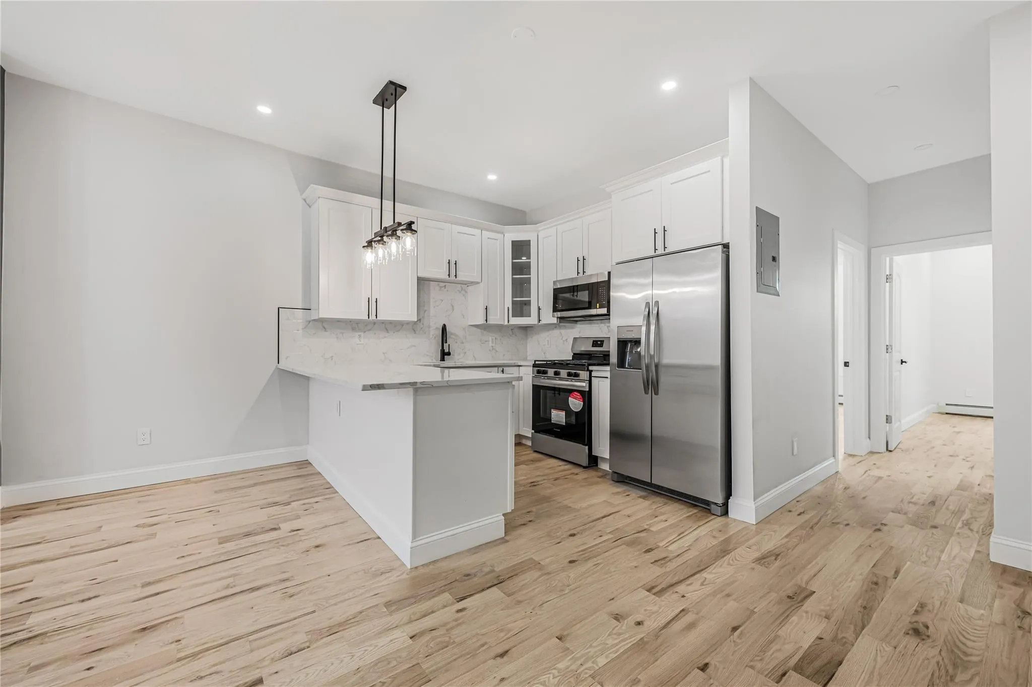 Kitchen featuring a peninsula, appliances with stainless steel finishes, white cabinets, light wood-style floors, and recessed lighting Kitchen featuring a peninsula, appliances with stainless steel finishes, white cabinets, light wood-style floors, and recessed lighting