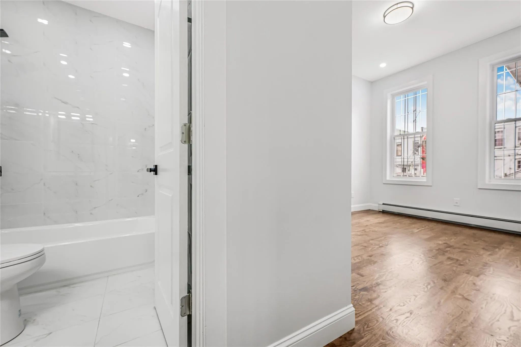 Full bath featuring shower / bathtub combination, recessed lighting, a baseboard radiator, and marble look tile flooring Full bath featuring shower / bathtub combination, recessed lighting, a baseboard radiator, and marble look tile flooring