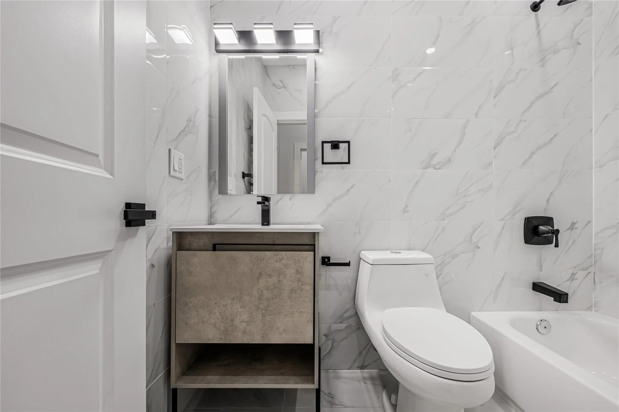 Bathroom featuring tile walls, vanity, and shower / bathtub combination Bathroom featuring tile walls, vanity, and shower / bathtub combination