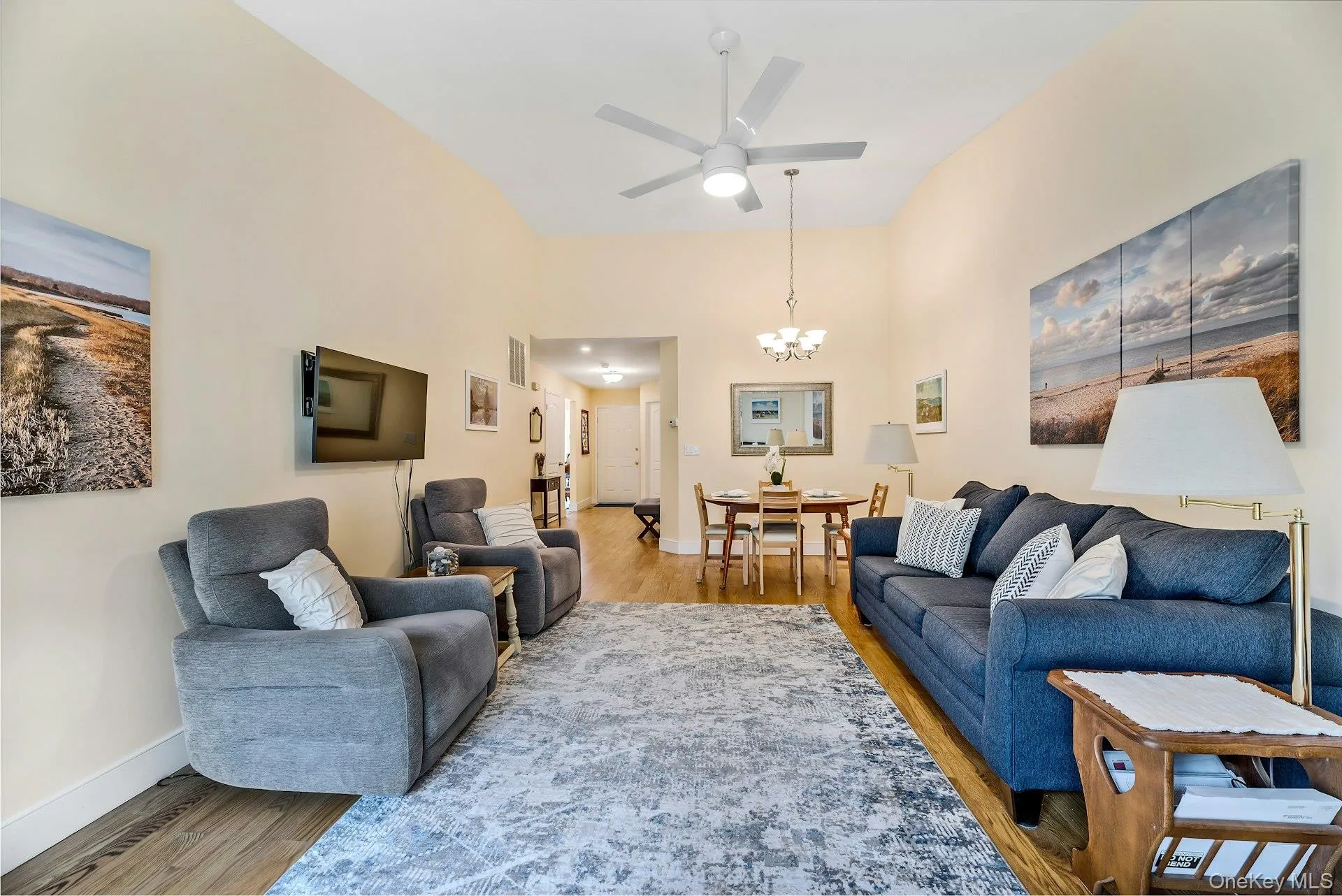 Living area featuring wood finished floors, a chandelier, and ceiling fan Living area featuring wood finished floors, a chandelier, and ceiling fan