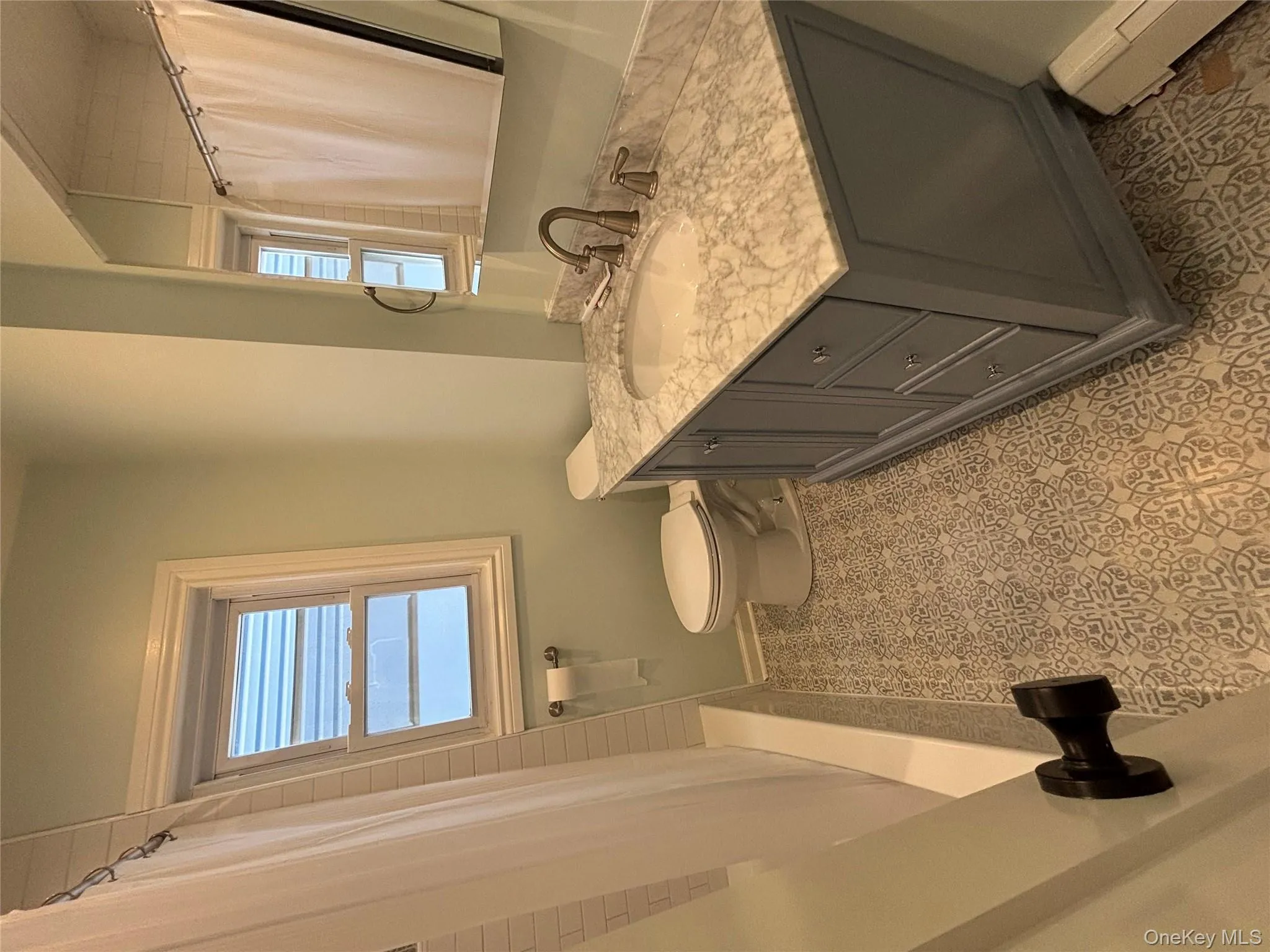 Bathroom featuring vanity, baseboard heating, and shower / bath combination with curtain Bathroom featuring vanity, baseboard heating, and shower / bath combination with curtain
