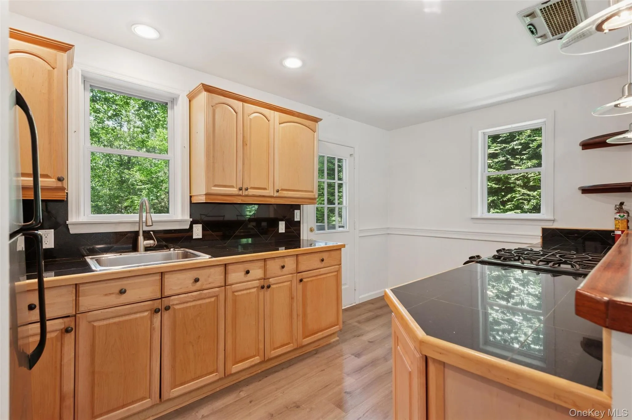 Kitchen featuring plenty of natural light, light brown cabinets, light wood-type flooring, and recessed lighting Kitchen featuring plenty of natural light, light brown cabinets, light wood-type flooring, and recessed lighting