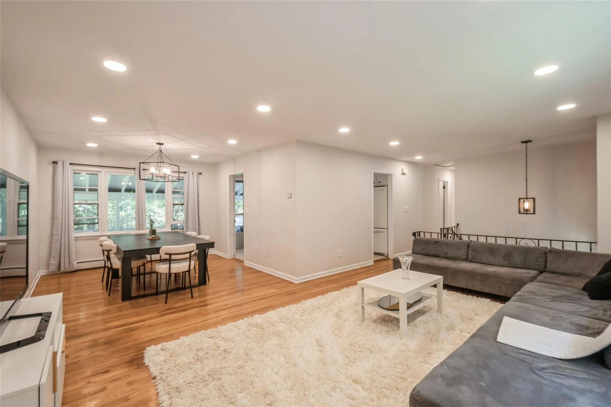 Living room featuring light wood-style flooring, a chandelier, and recessed lighting Living room featuring light wood-style flooring, a chandelier, and recessed lighting
