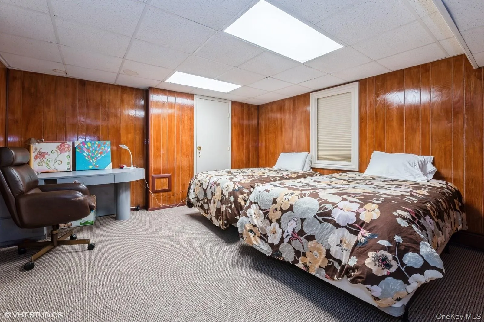 Bedroom with carpet, a drop ceiling, and wood walls Bedroom with carpet, a drop ceiling, and wood walls
