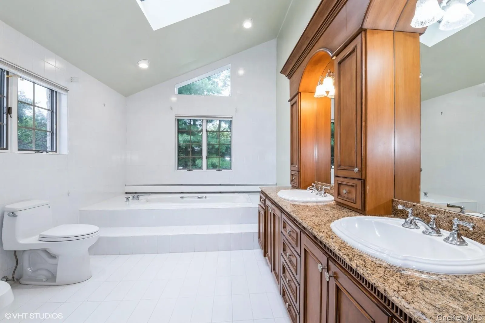 Bathroom with a skylight, lofted ceiling, a bath, light tile patterned flooring, and recessed lighting Bathroom with a skylight, lofted ceiling, a bath, light tile patterned flooring, and recessed lighting