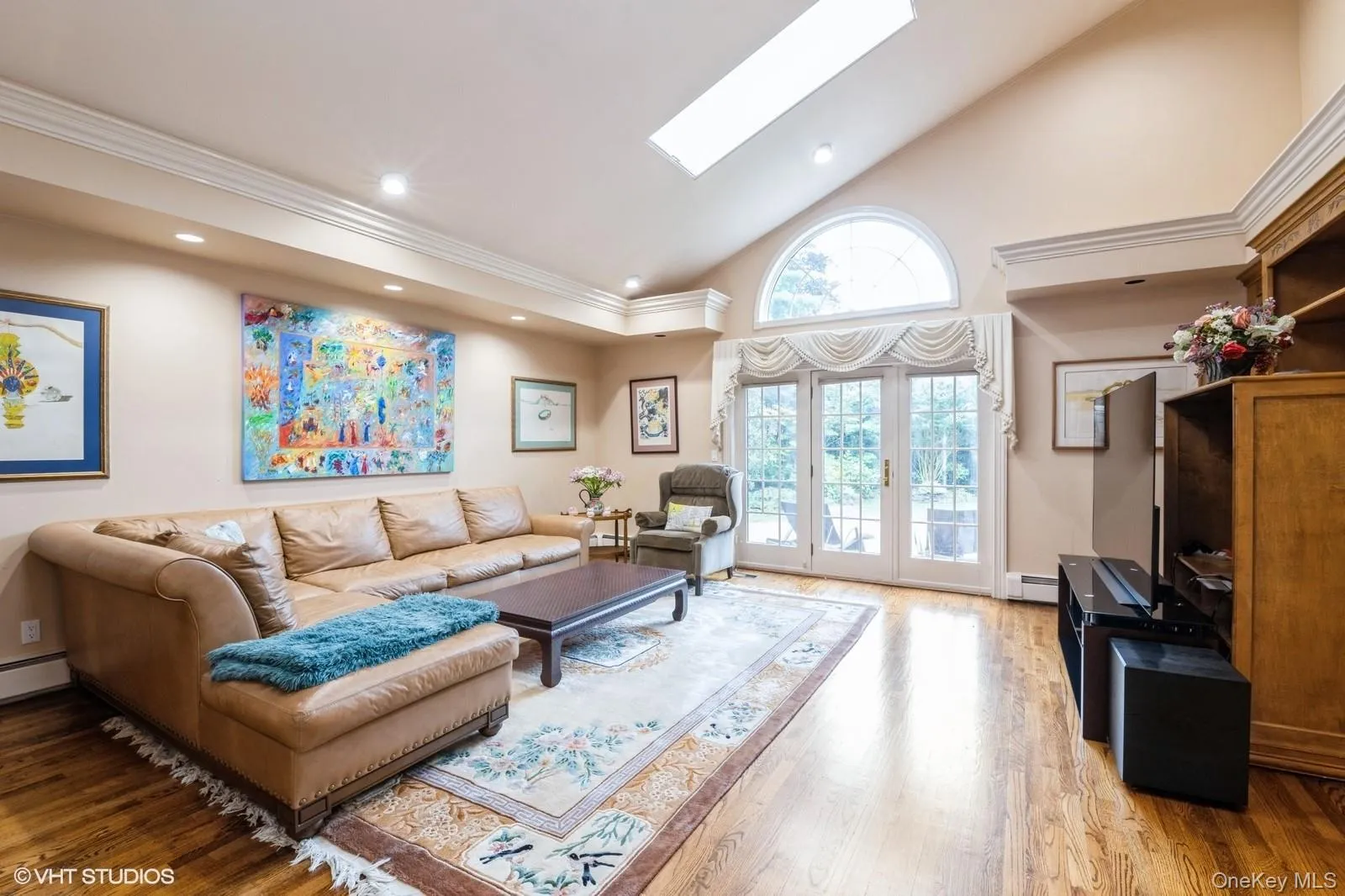 Living area with high vaulted ceiling, a skylight, wood finished floors, recessed lighting, and french doors Living area with high vaulted ceiling, a skylight, wood finished floors, recessed lighting, and french doors