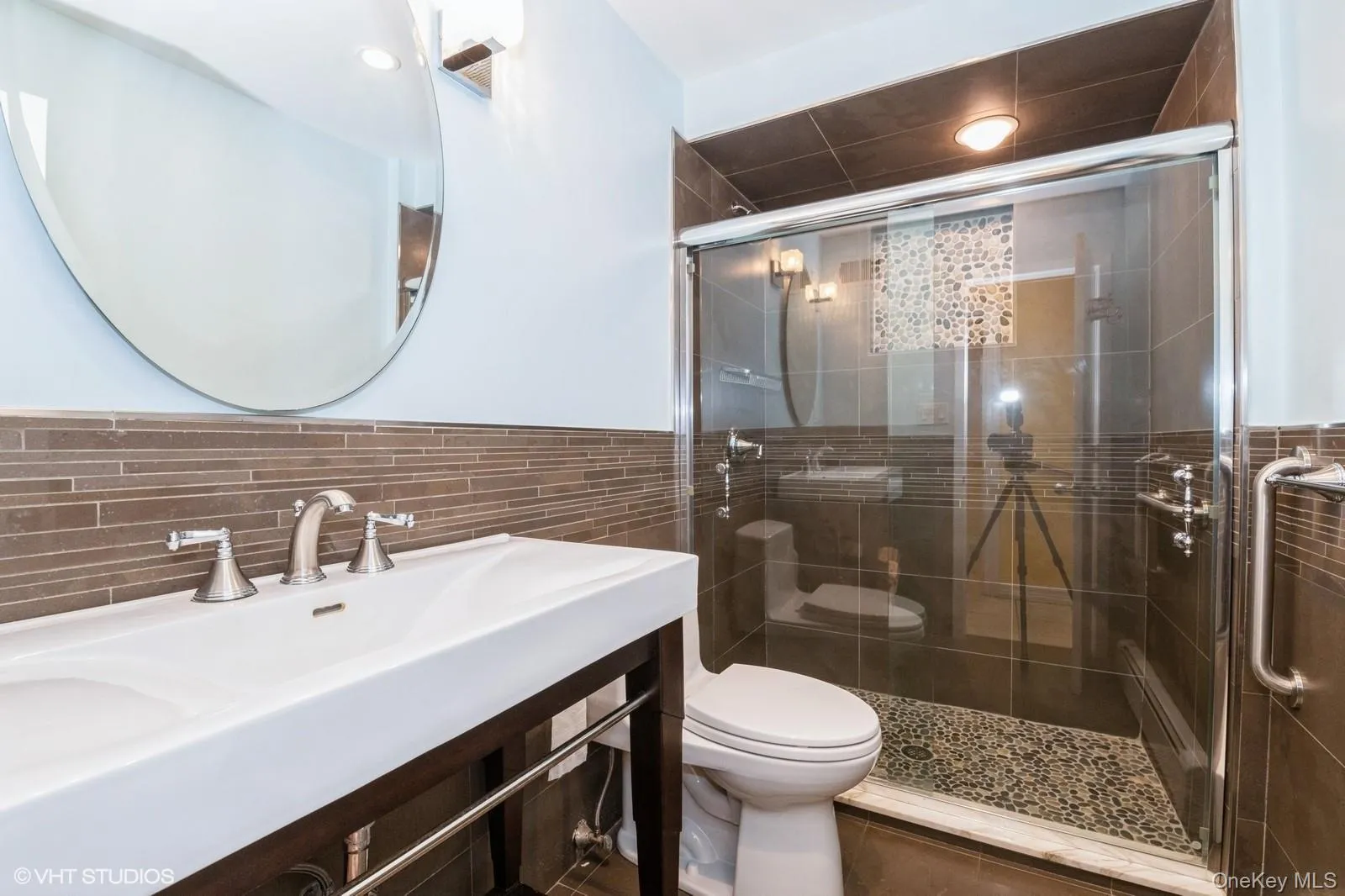 Bathroom with a shower stall, tile walls, and a wainscoted wall Bathroom with a shower stall, tile walls, and a wainscoted wall