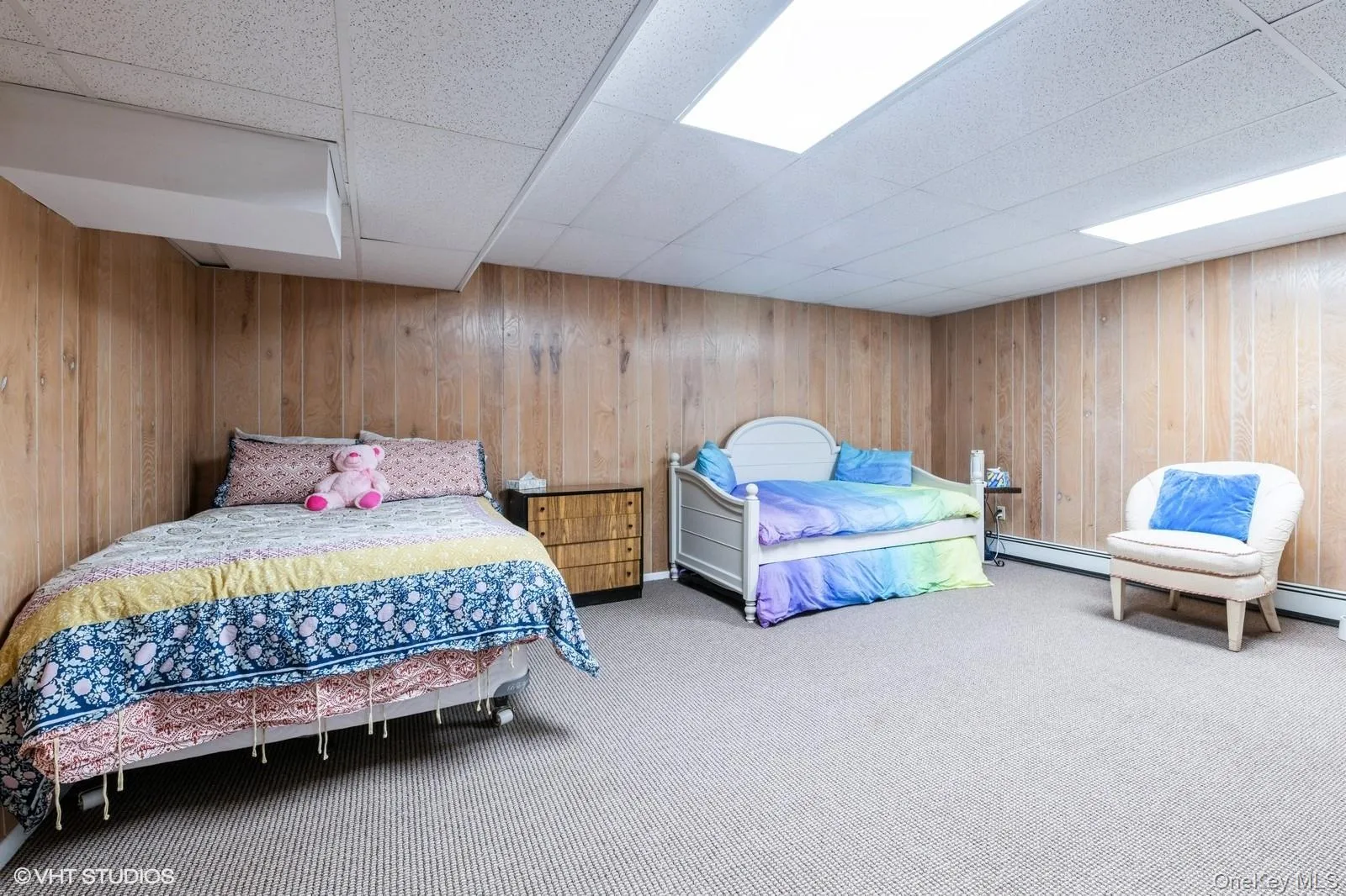 Carpeted bedroom featuring a drop ceiling, wood walls, and a baseboard radiator Carpeted bedroom featuring a drop ceiling, wood walls, and a baseboard radiator