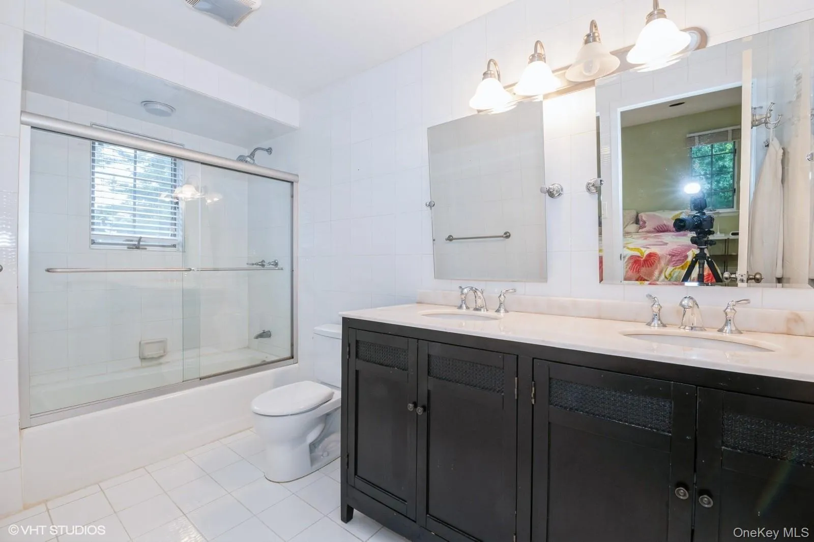 Bathroom with tile walls, connected bathroom, enclosed tub / shower combo, and light tile patterned floors Bathroom with tile walls, connected bathroom, enclosed tub / shower combo, and light tile patterned floors