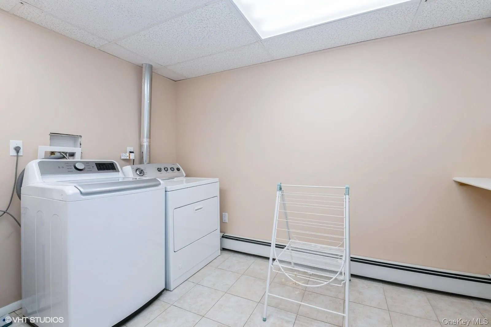 Laundry room with light tile patterned floors, separate washer and dryer, and a baseboard radiator Laundry room with light tile patterned floors, separate washer and dryer, and a baseboard radiator