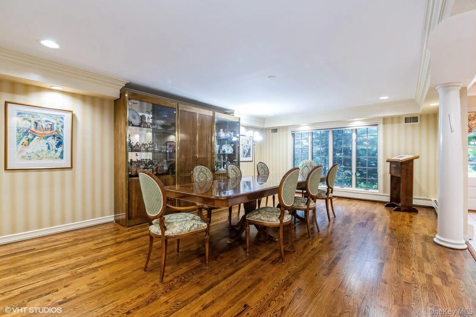 Dining area with wallpapered walls, wood finished floors, ornamental molding, ornate columns, and recessed lighting Dining area with wallpapered walls, wood finished floors, ornamental molding, ornate columns, and recessed lighting