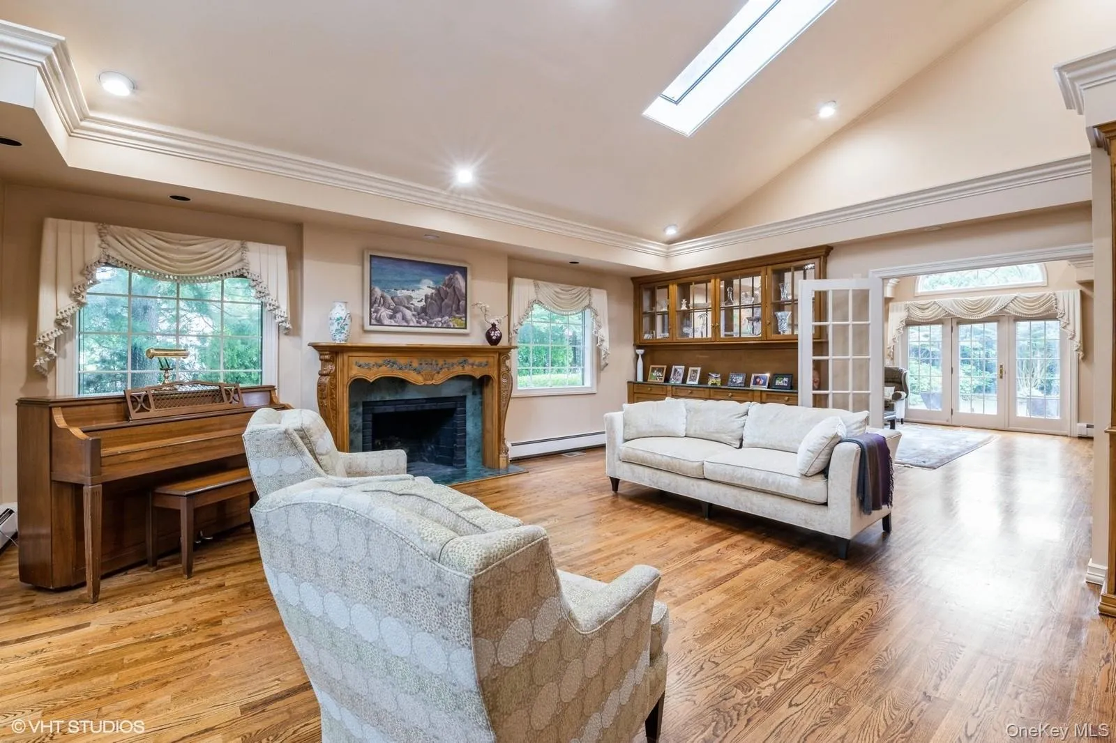 Living area with french doors, high vaulted ceiling, light wood-style floors, recessed lighting, and a fireplace Living area with french doors, high vaulted ceiling, light wood-style floors, recessed lighting, and a fireplace