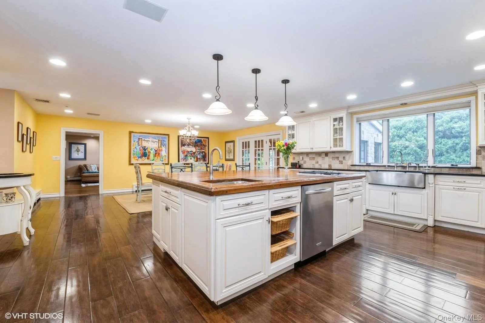 Kitchen featuring backsplash, a chandelier, white cabinets, decorative light fixtures, and dark wood-style floors Kitchen featuring backsplash, a chandelier, white cabinets, decorative light fixtures, and dark wood-style floors