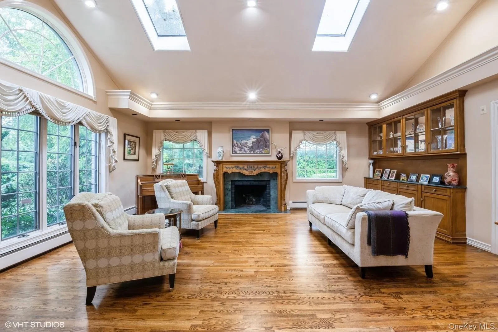 Living room with a skylight, a premium fireplace, light wood finished floors, recessed lighting, and high vaulted ceiling Living room with a skylight, a premium fireplace, light wood finished floors, recessed lighting, and high vaulted ceiling