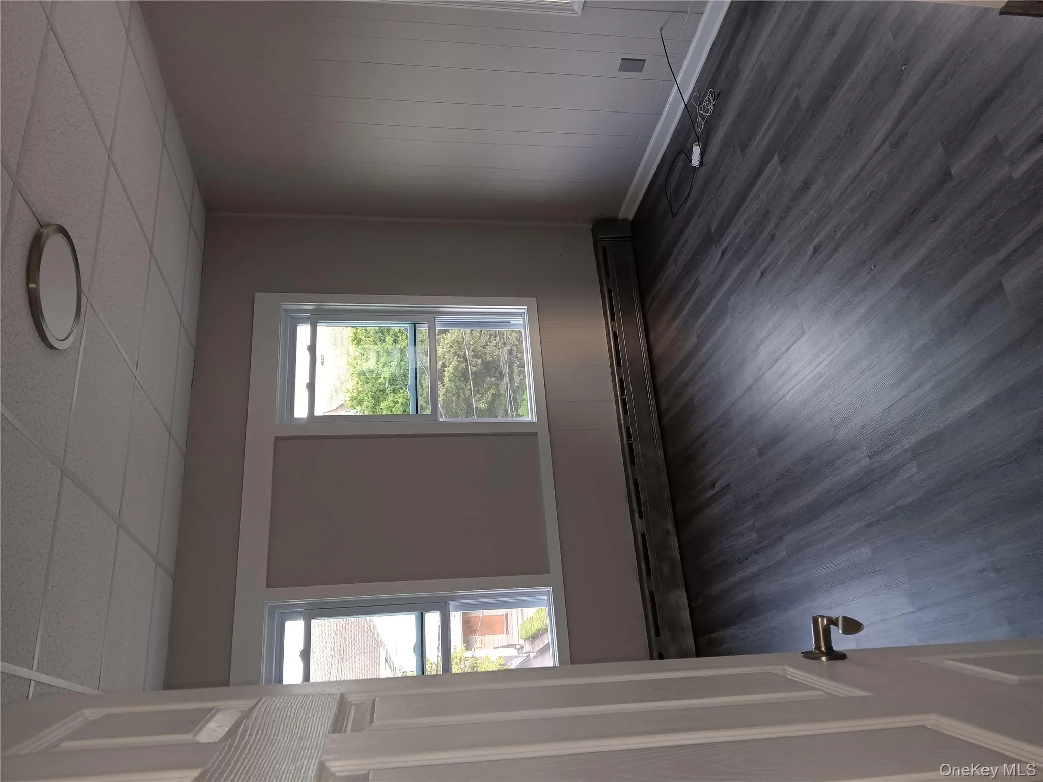 Empty room featuring wood finished floors, a paneled ceiling, and a baseboard heating unit Empty room featuring wood finished floors, a paneled ceiling, and a baseboard heating unit