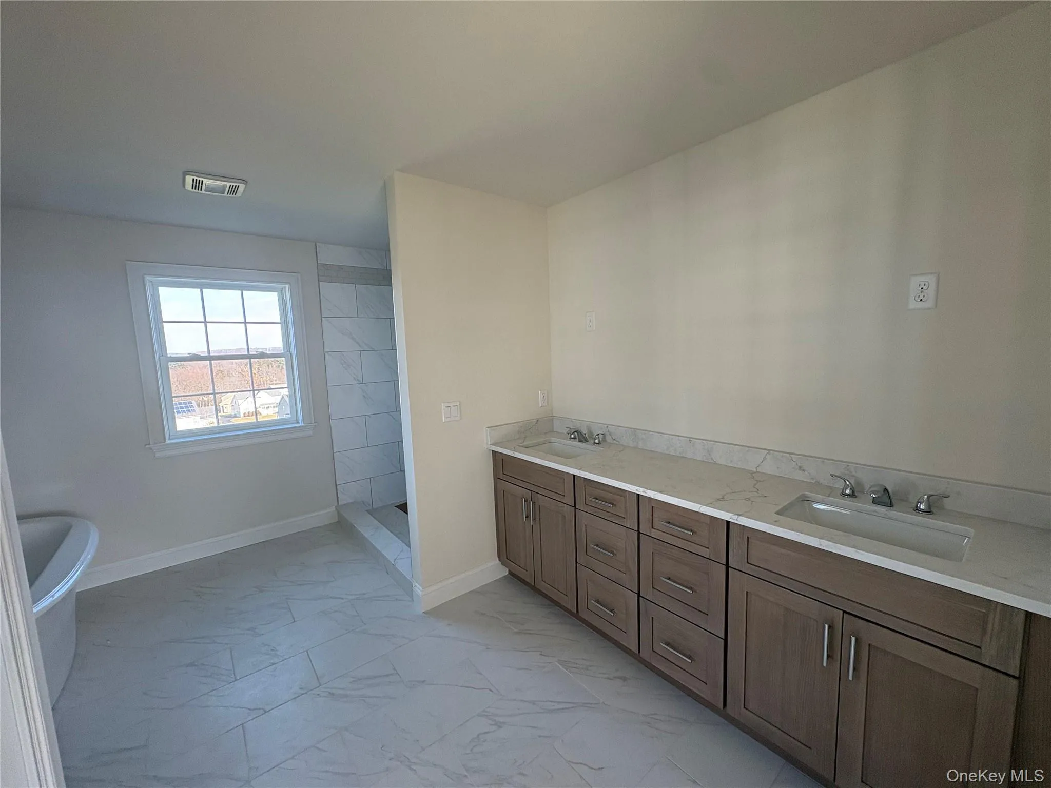 Bathroom with a soaking tub, double vanity, light marble finish flooring, and walk in shower Bathroom with a soaking tub, double vanity, light marble finish flooring, and walk in shower