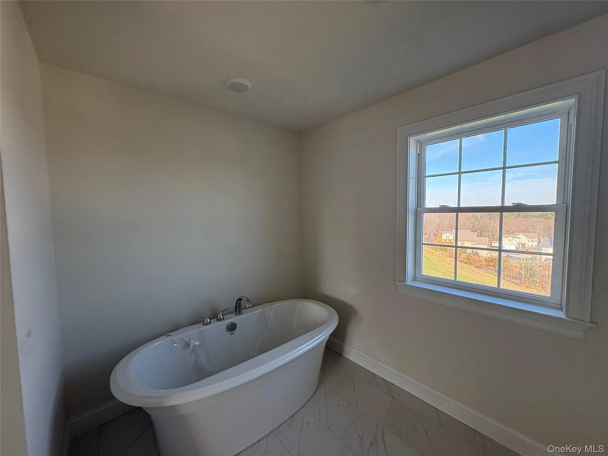 Full bathroom featuring marble finish floors and a soaking tub Full bathroom featuring marble finish floors and a soaking tub