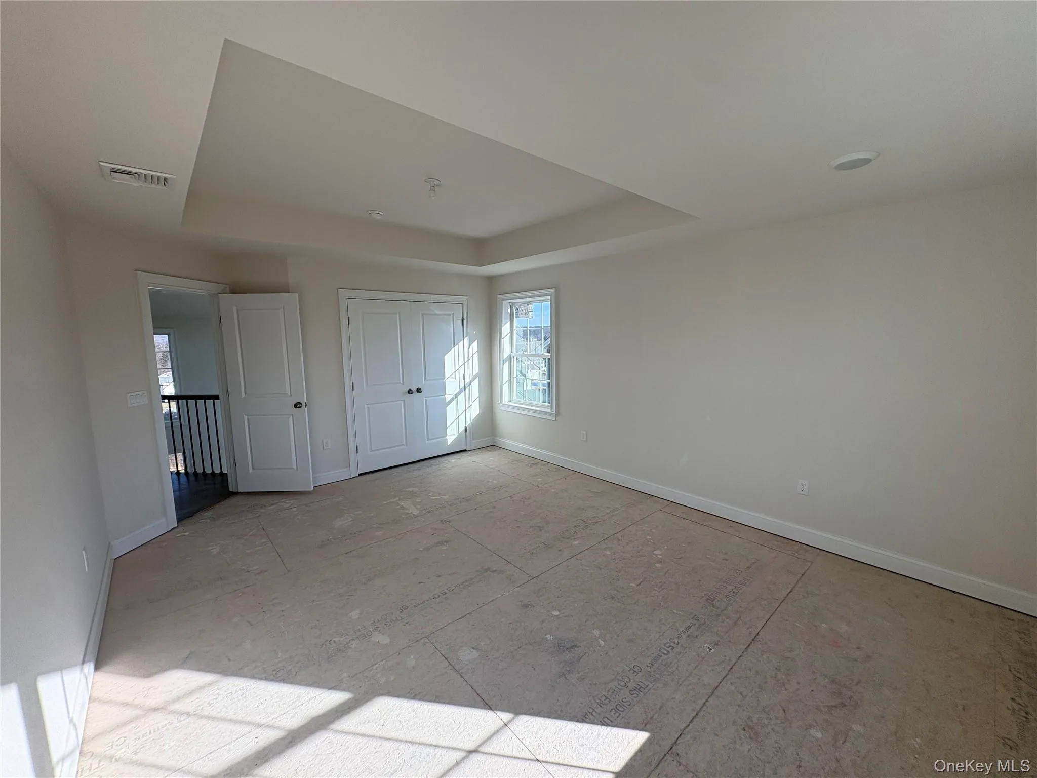 Unfurnished bedroom featuring a tray ceiling and a closet Unfurnished bedroom featuring a tray ceiling and a closet
