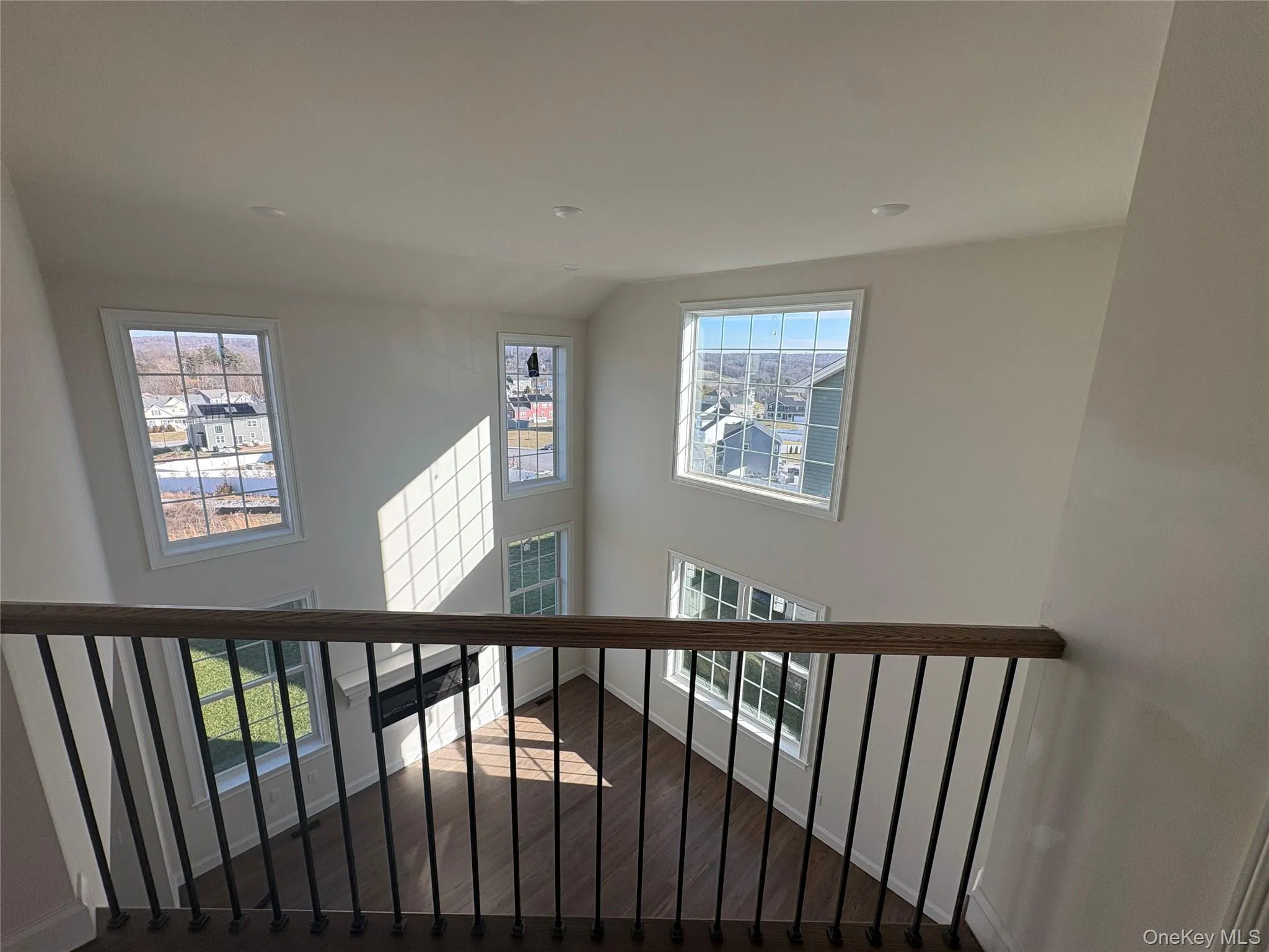 Stairs featuring wood finished floors, a towering ceiling, and healthy amount of natural light Stairs featuring wood finished floors, a towering ceiling, and healthy amount of natural light