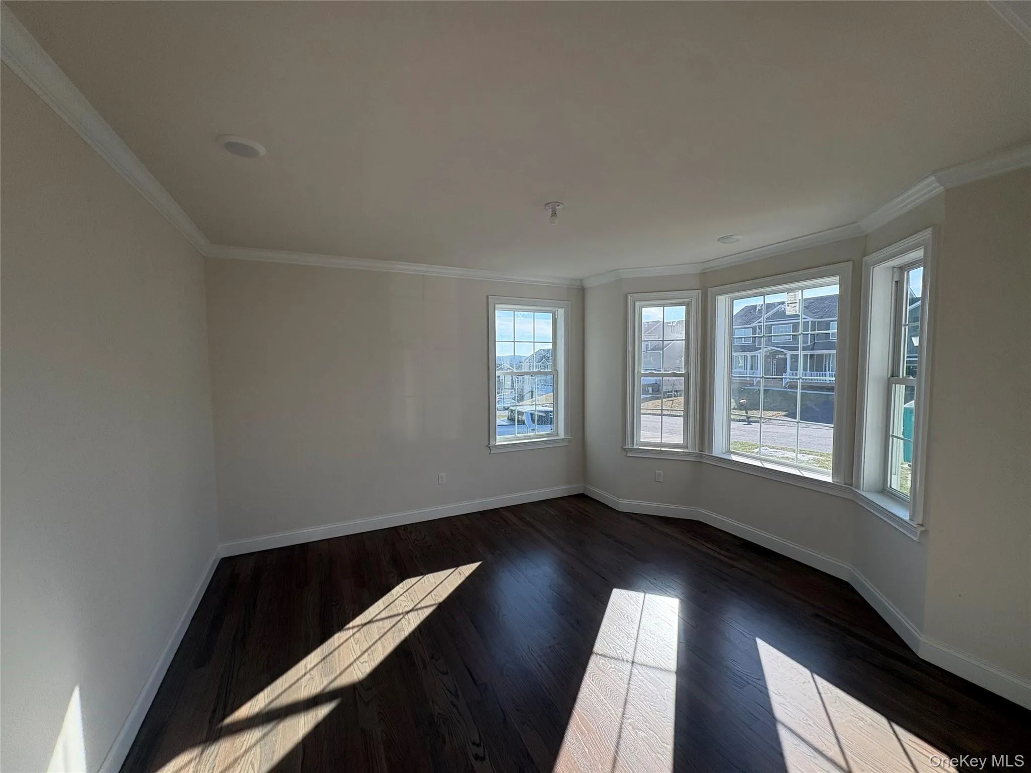 Unfurnished room with crown molding and dark wood finished floors Unfurnished room with crown molding and dark wood finished floors