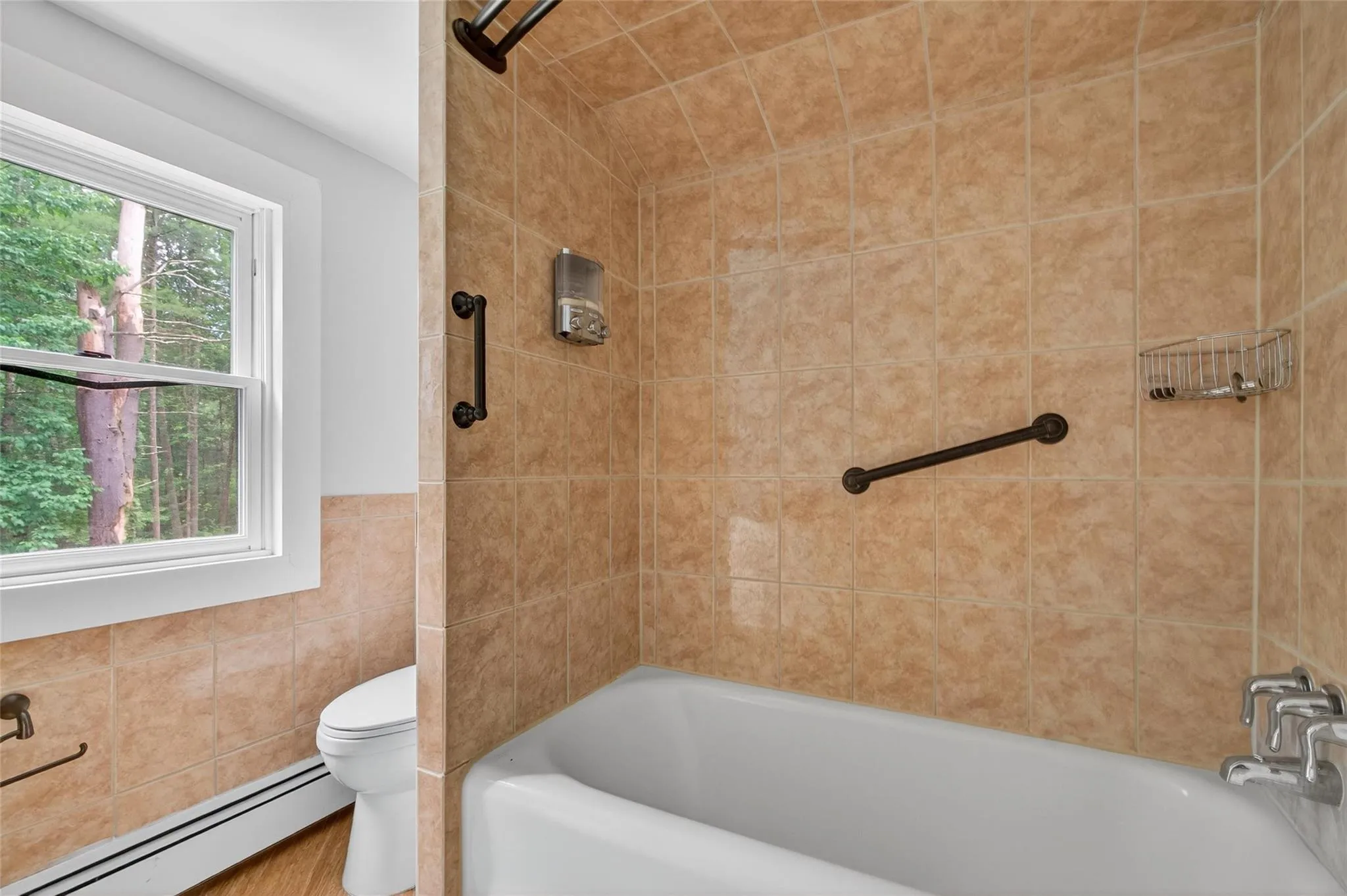 Bathroom with baseboard heating, shower / bath combination, and tile walls Bathroom with baseboard heating, shower / bath combination, and tile walls