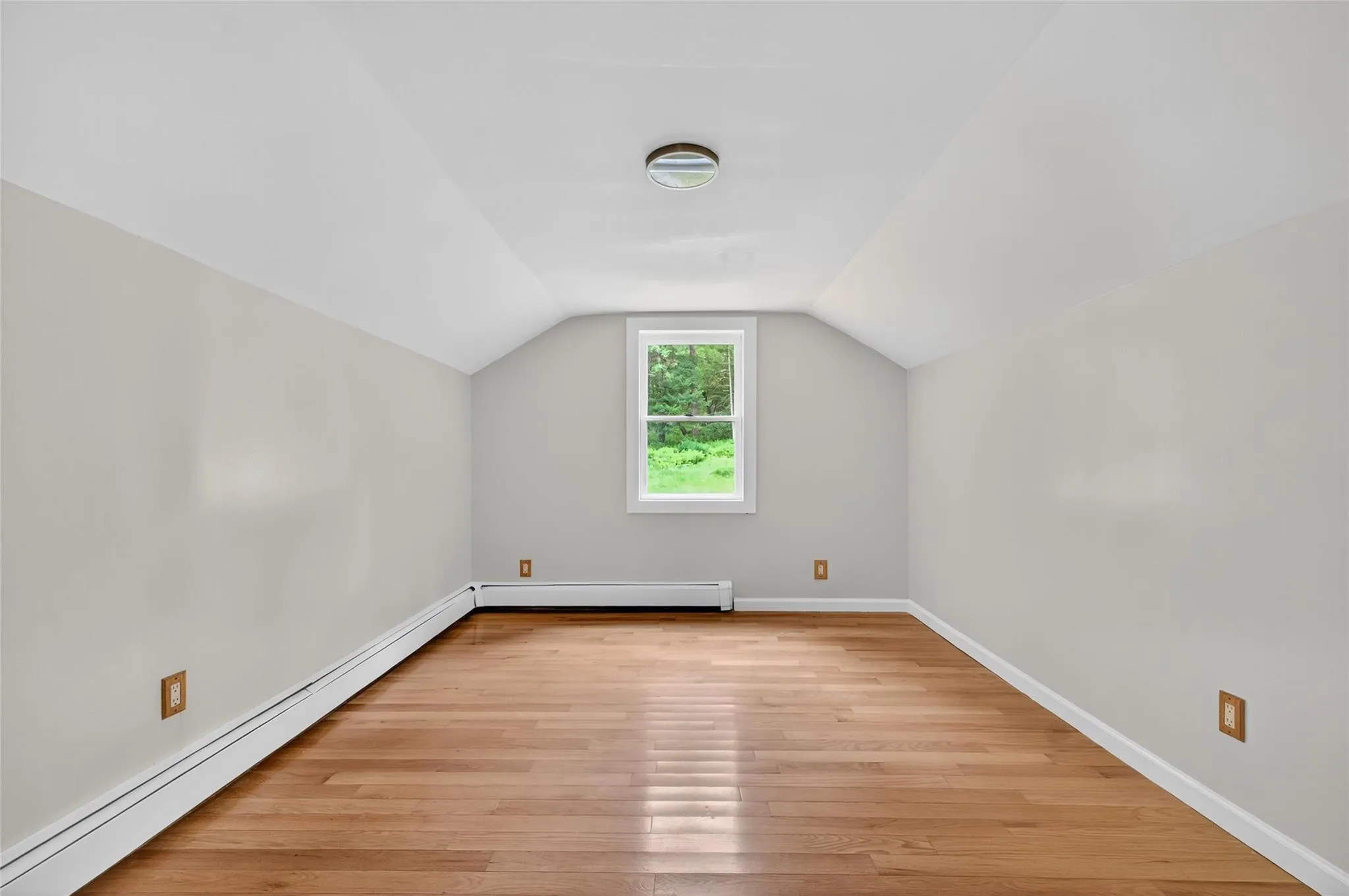 Bonus room featuring a baseboard heating unit, light wood-style floors, and vaulted ceiling Bonus room featuring a baseboard heating unit, light wood-style floors, and vaulted ceiling