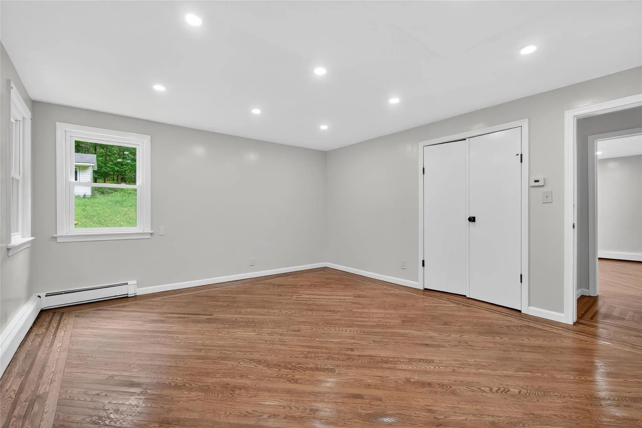 Unfurnished bedroom featuring wood finished floors, recessed lighting, a closet, and baseboard heating Unfurnished bedroom featuring wood finished floors, recessed lighting, a closet, and baseboard heating
