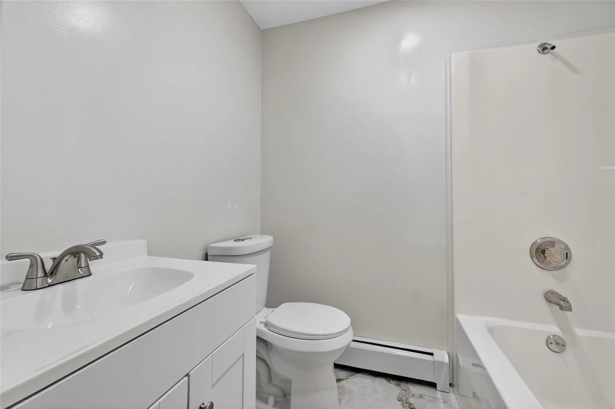 Full bathroom featuring baseboard heating, vanity, marble look tile flooring, and tub / shower combination Full bathroom featuring baseboard heating, vanity, marble look tile flooring, and tub / shower combination
