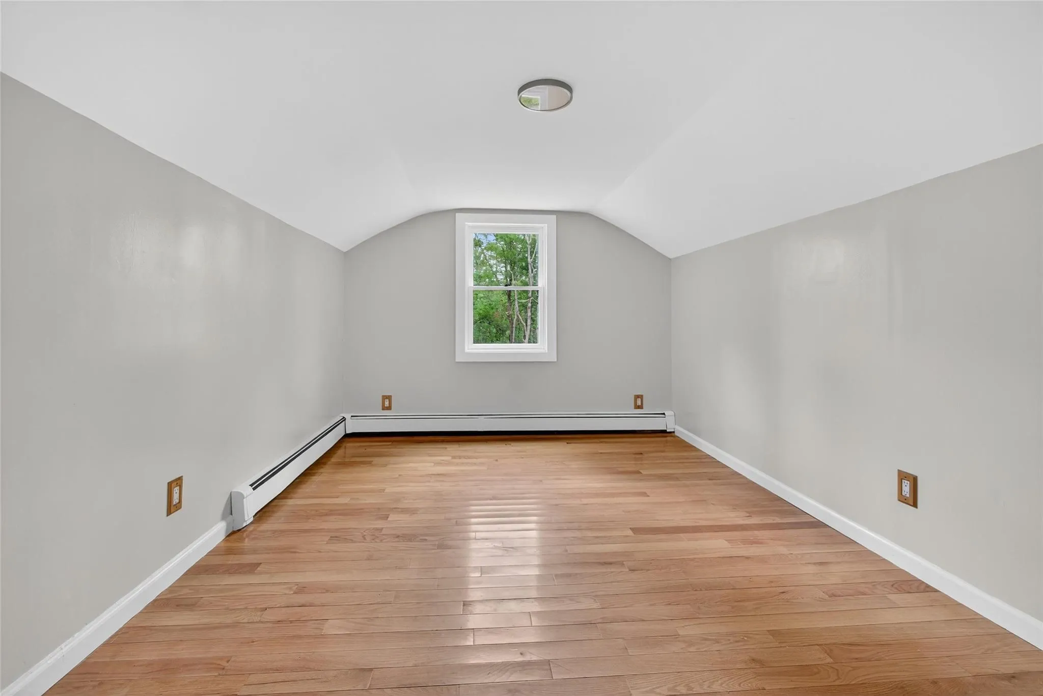 Bonus room with light wood-style flooring, lofted ceiling, and a baseboard radiator Bonus room with light wood-style flooring, lofted ceiling, and a baseboard radiator