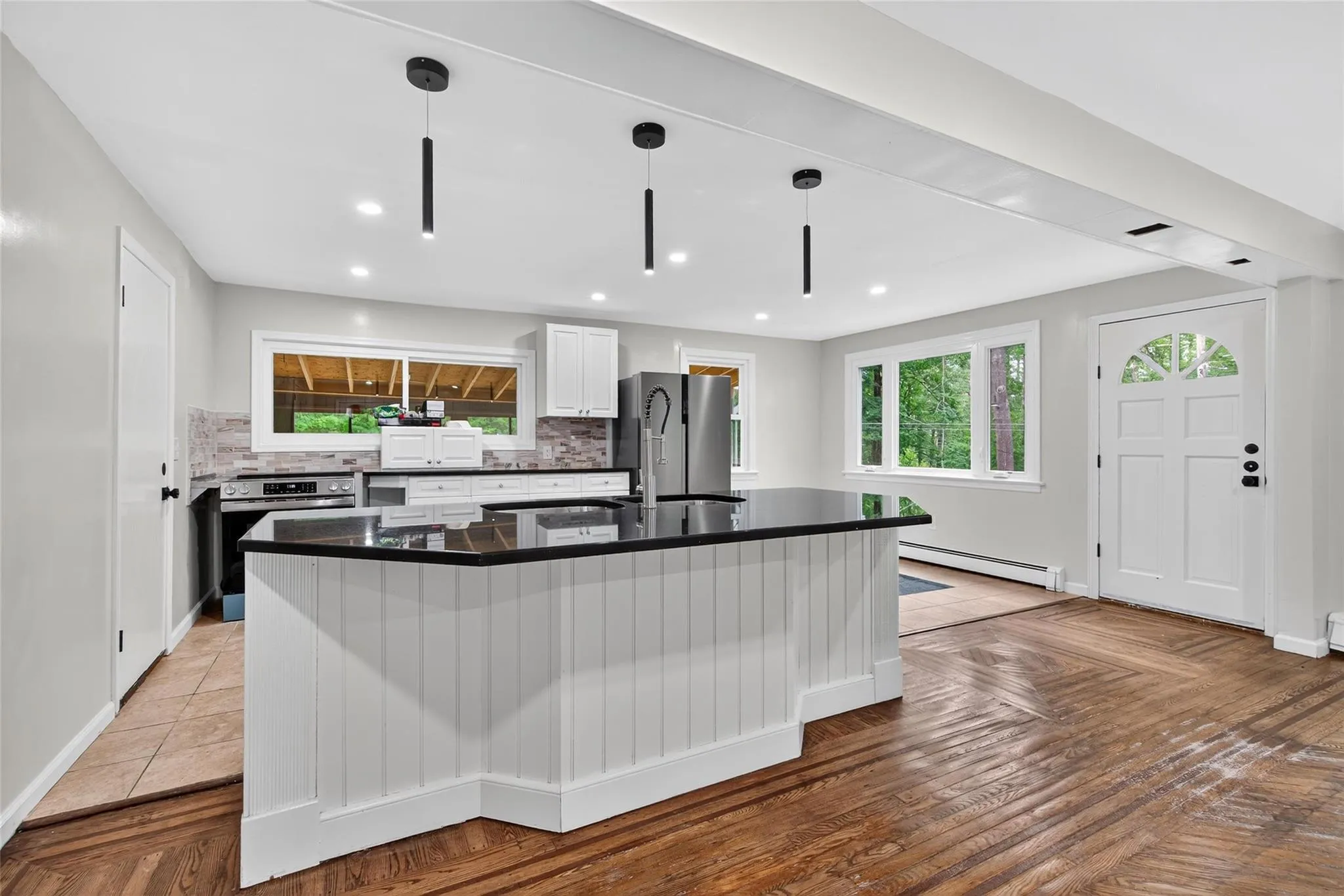 Kitchen featuring freestanding refrigerator, wall oven, a baseboard heating unit, tasteful backsplash, and white cabinetry Kitchen featuring freestanding refrigerator, wall oven, a baseboard heating unit, tasteful backsplash, and white cabinetry