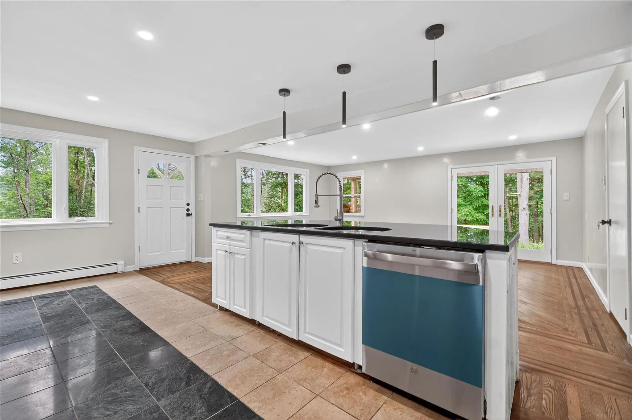 Kitchen with dishwasher, dark countertops, a baseboard heating unit, recessed lighting, and white cabinets Kitchen with dishwasher, dark countertops, a baseboard heating unit, recessed lighting, and white cabinets