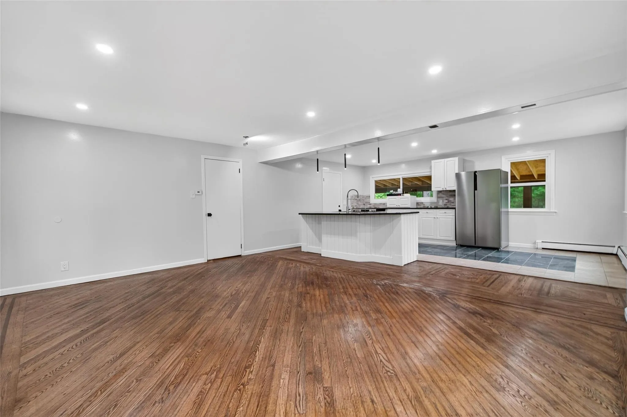 Unfurnished living room featuring dark wood-style flooring, recessed lighting, and a baseboard radiator Unfurnished living room featuring dark wood-style flooring, recessed lighting, and a baseboard radiator