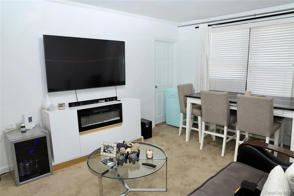 Living area with light colored carpet, crown molding, and wine cooler Living area with light colored carpet, crown molding, and wine cooler