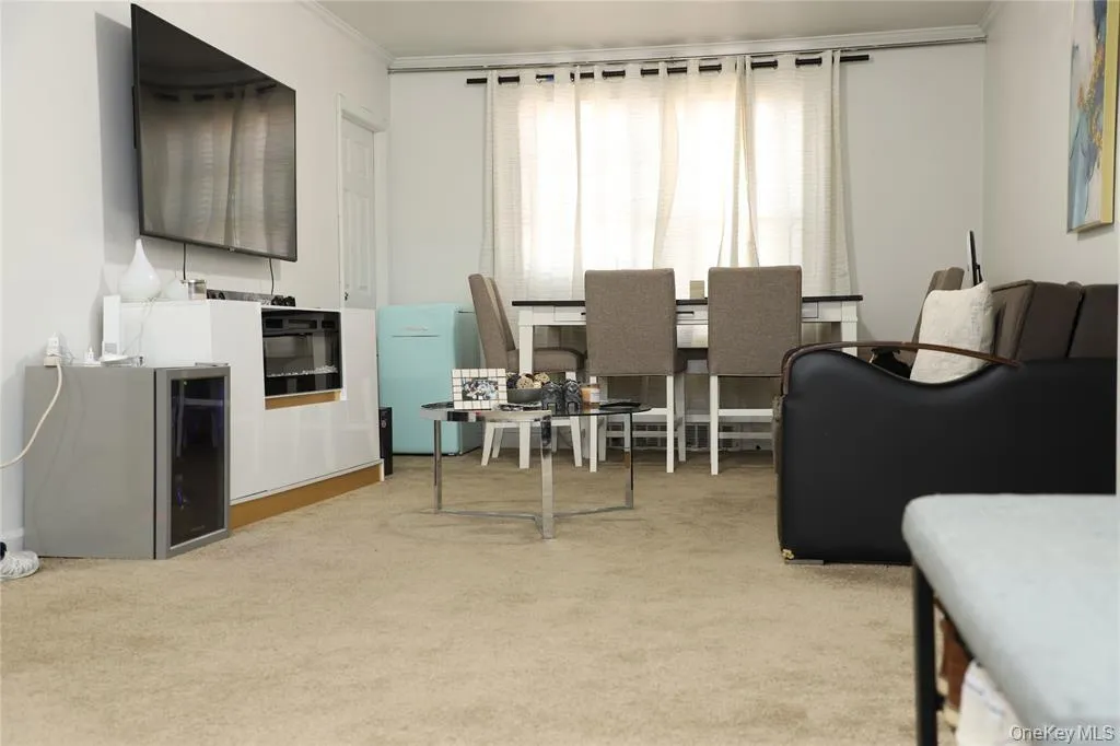 Carpeted living area featuring ornamental molding and wine cooler Carpeted living area featuring ornamental molding and wine cooler