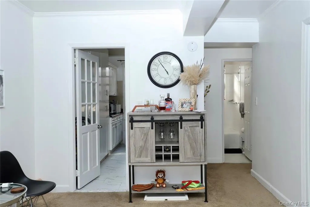 Hallway with light colored carpet, crown molding, and light marble finish floors Hallway with light colored carpet, crown molding, and light marble finish floors